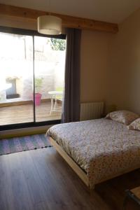 a bedroom with a bed and a view of a deck at La maison du Plo in Fabrezan