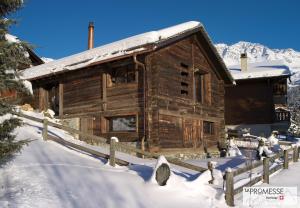 ein Blockhaus im Schnee mit einem Zaun in der Unterkunft Chalet "La Promesse" in Bagnes