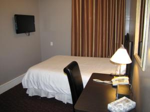 Habitación de hotel con cama y escritorio con lámpara. en Barclay Hotel, en Vancouver