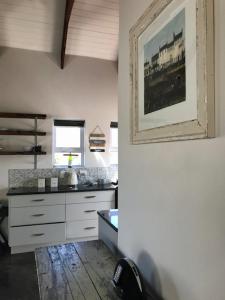 una cocina con armarios blancos y una foto en la pared en Stylish Country Cottage, Solar panelled in Knysna en Knysna