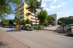 an empty street with cars parked in front of a building at Appartamenti Atlante in Bibione