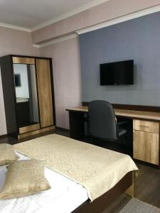 1 dormitorio con 2 camas, escritorio y TV en ORIENT en Osh