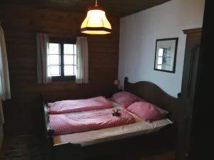 Schlafzimmer mit einem Bett mit rosa Kissen und einer Lampe in der Unterkunft Appartement Sonnleitn in Sonnenalpe Nassfeld