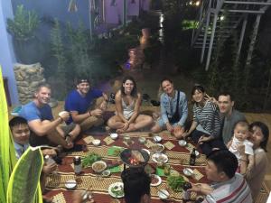 Un groupe de personnes assises autour d'une table dans l'établissement Phong Nha Friendly Home, à Phong Nha