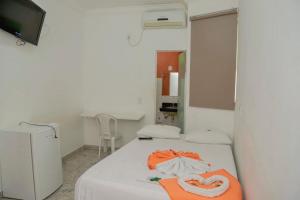 a small room with a bed with an orange towel on it at Hotel Cco Goiânia in Goiânia