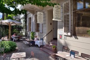 una mujer sentada en una mesa fuera de un restaurante en Gast - und Kulturhaus Der Teufelhof Basel en Basilea