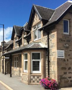 une maison en pierre avec des fleurs devant elle dans l'établissement Clune House B&B, à Newtonmore