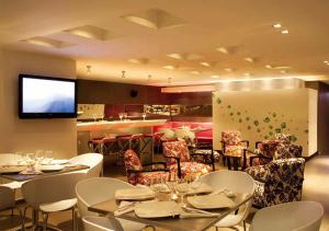 a restaurant with white tables and chairs and a television at San Simon Hotel Pereira in Pereira