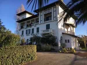 a white building with a palm tree in front of it at Domaine de Bordaberry in Urrugne