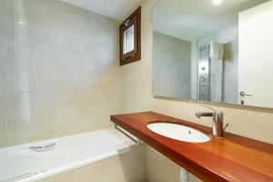 een badkamer met een wastafel, een spiegel en een bad bij Masia el Prat in El Pont de Vilomara