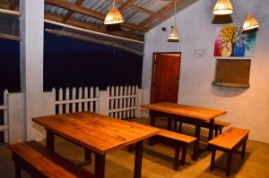 3 tables et bancs en bois dans une pièce dans l'établissement Victorian Guest, à Bandarawela