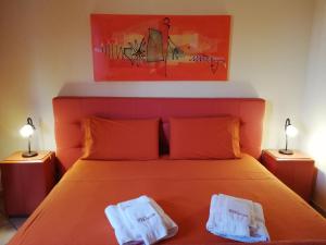 a bedroom with an orange bed with two white towels on it at B&B Domus Traiani Benevento in Benevento