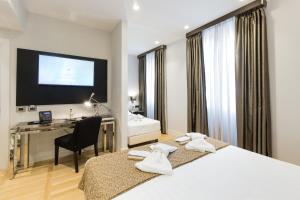 a hotel room with two beds and a desk and a television at Floris Hotel in Rome