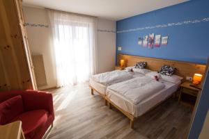 a bedroom with two beds and a blue wall at Hotel Montana in Fai della Paganella