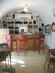 a restaurant with red chairs and a counter with wine bottles at Le Vin de l'Eté in Ponet-et-Saint-Auban