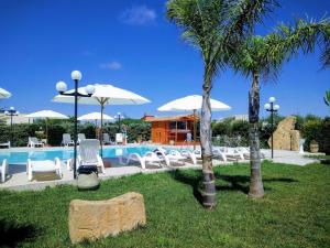 um resort com piscina, cadeiras e palmeiras em Lilybeo Village em Marsala