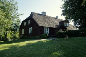 a brown house with a dog standing in front of it at Brīvdienu māja Kažoki in Ēdole