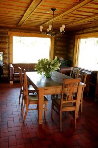 una mesa de madera con sillas y un jarrón de flores. en Brīvdienu māja Kažoki, en Ēdole