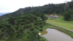 una casa en una colina junto a un cuerpo de agua en Sitio Itaimbé - Casa e Chalé - Morro da Igreja, en Urubici
