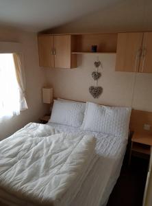 a large white bed in a bedroom with a window at S460 8 BERTH CARAVAN ON THE GOLDEN PALM CHAPEL ST LEONARDS in Chapel Saint Leonards