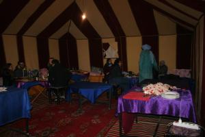 a group of people sitting at tables in a tent at Zagora Desert Camp in Bou Khellal
