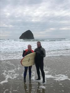 a man and woman standing on the beach with a surfboard at Inn at Cape Kiwanda in Pacific City