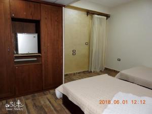 1 dormitorio con 1 cama y TV en la pared en St. Marie House, en Asiut