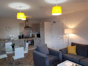 a living room with two couches and a table and a kitchen at 1 Royal View Apartments in Stirling