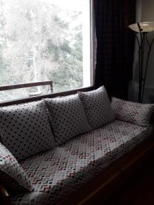 a couch with pillows in front of a window at margue residence meledrio in Folgarida
