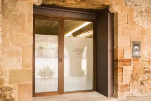 a glass door to a building with a sign on it at Habitacions Plaça Major in Santa Pau