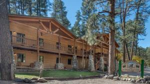 a large log cabin in the woods with trees at Upper Canyon Inn & Cabins in Ruidoso