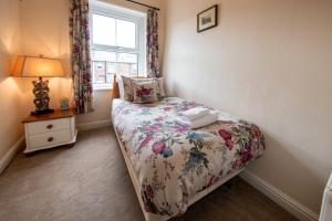 ハロゲートにあるHarrogate 100のベッドルーム1室(花柄のベッドカバー、窓付)