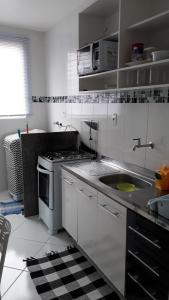 cocina blanca con fregadero y fogones en Apartamento Orquídea en Campos dos Goytacazes