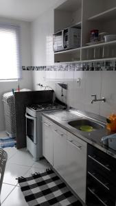 a white kitchen with a sink and a stove at Apartamento Orquídea in Campos dos Goytacazes +8 photos
