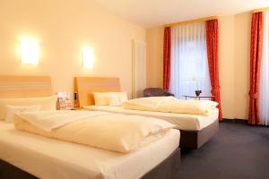 
a hotel room with two beds and two lamps at Hotel Theresientor in Straubing
