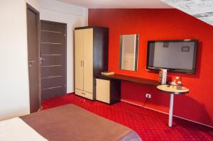 Habitación roja con TV, cama y lavabo. en GP Hotel, en Ploieşti