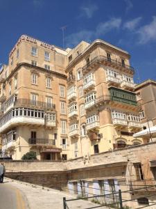 un grand bâtiment avec un homme debout devant lui dans l'établissement Grand Harbour Hotel, à La Valette