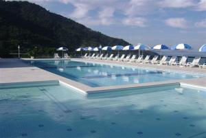 a large swimming pool with chairs and umbrellas at Apartamento no Porto Real Resort com vista para o mar in Mangaratiba