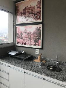 a kitchen counter with a sink and two pictures on the wall at APTO Bras expo center 25 marco Feirinha Da Madrugada - ESPAÇO INTEIRO in Sao Paulo