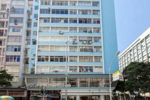 um edifício azul alto no meio de uma cidade em Flat Hilário no Rio de Janeiro