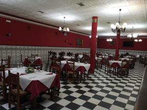 un restaurante con mesas, sillas y paredes rojas en Hostal El Camionero, en Burguillos del Cerro
