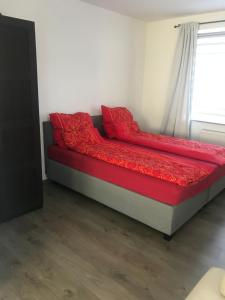 a bed in a room with red sheets and a window at Wohnung am Phönixsee in Dortmund