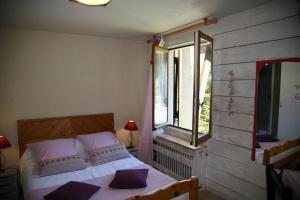 Un dormitorio con una cama con almohadas moradas y una ventana en Hôtel Le Glacier, en Gourette