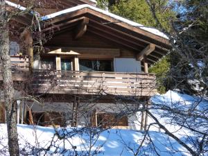una cabaña en el bosque con nieve en el suelo en Ferienwohnung Laax mit Traumblick, großem Balkon und Terrasse, en Laax