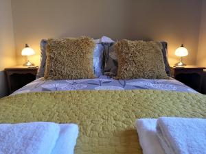 Duck Cottage في ثيرسك: سرير مع وسادتين عليه مصباحين