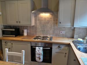 a kitchen with a stove top oven next to a sink at Duck Cottage in Thirsk