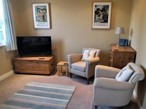 a living room with two chairs and a flat screen tv at Duck Cottage in Thirsk