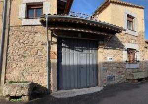 a stone building with a large garage door at Casa Rural La Vertedera III in Villar de Ciervo