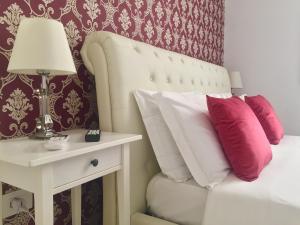 a bed with pink and white pillows and a table with a lamp at Dimora San Biagio Suites&Apartment in Lecce