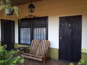 
a wooden bench sitting in front of a house at Dos Palmas Studio Apartments in Alajuela
